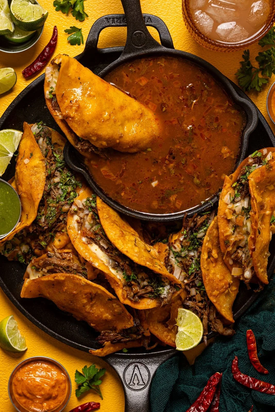 Delicious birria tacos served with consomรฉ and fresh toppings